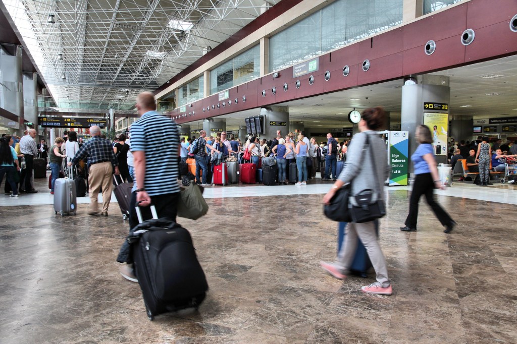 Passengers inside Tenerife airport with suitcases. 