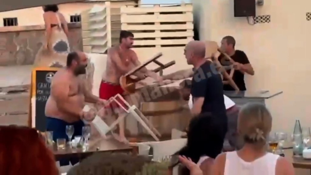Shirtless men wield chairs and bar stools during the brawl